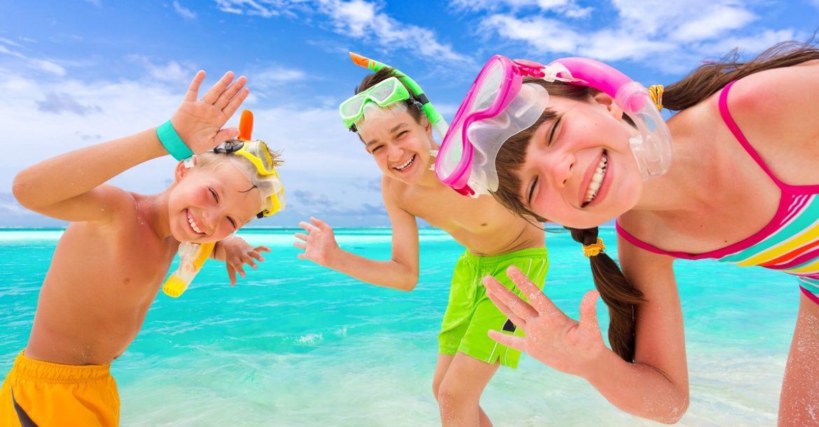 Kids in snorkel gear next to blue ocean.