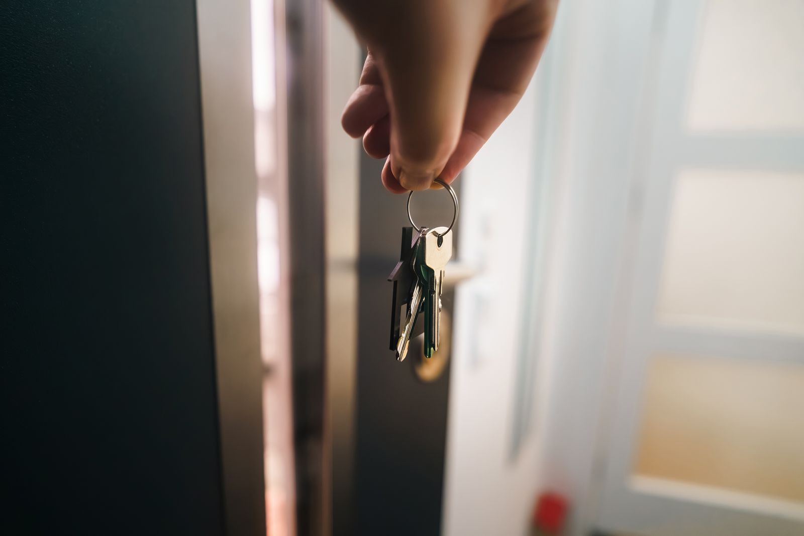 Hand holding a set of house keys in the open doorway of a home